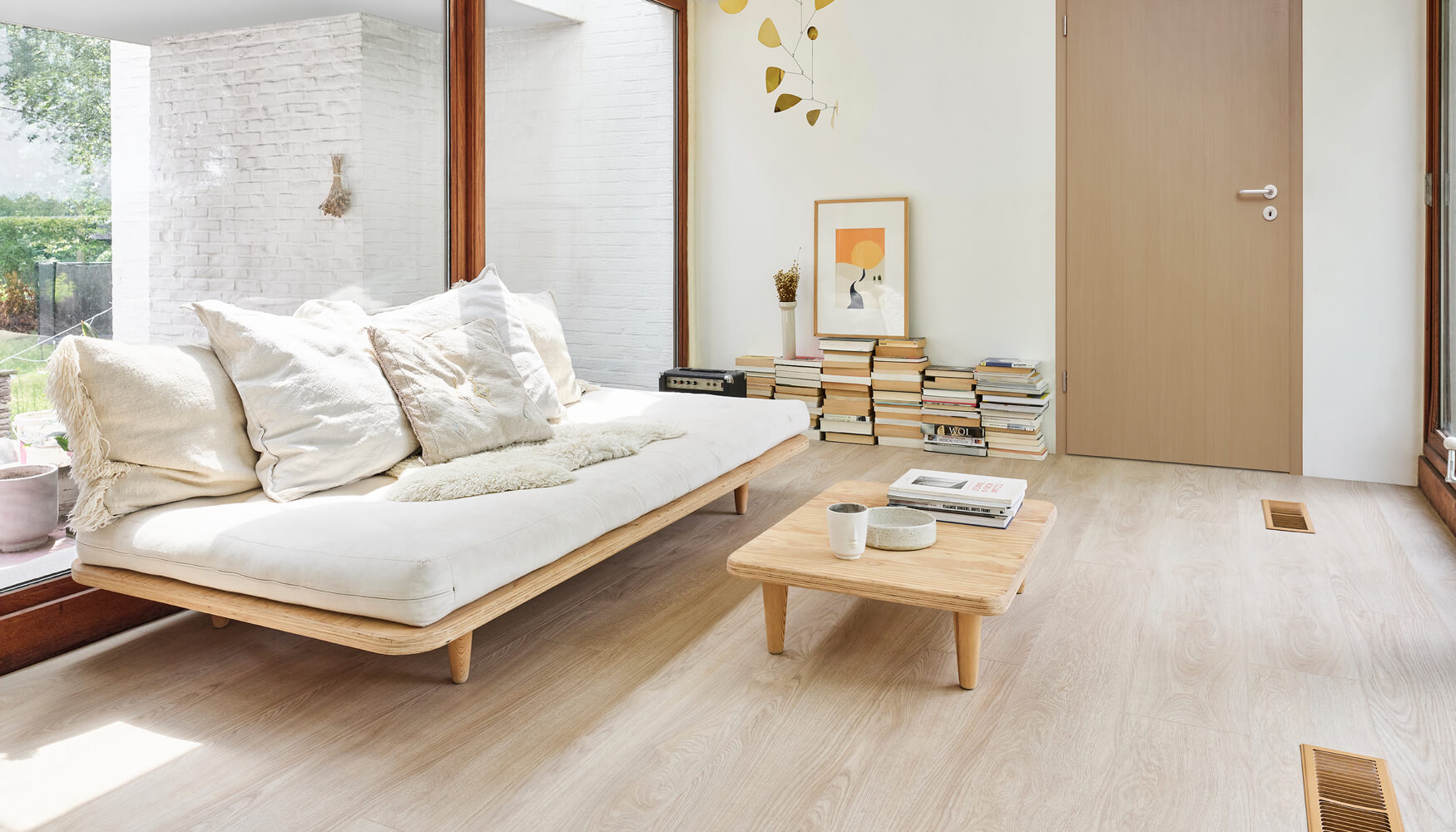 Intérieur d'une chambre à coucher avec un lit contre un mur avec un papier peint floral. Le sol présenté est le revêtement de sol vinyle de luxe Moduleo LayRed Laurel Oak 51230 Embossed.